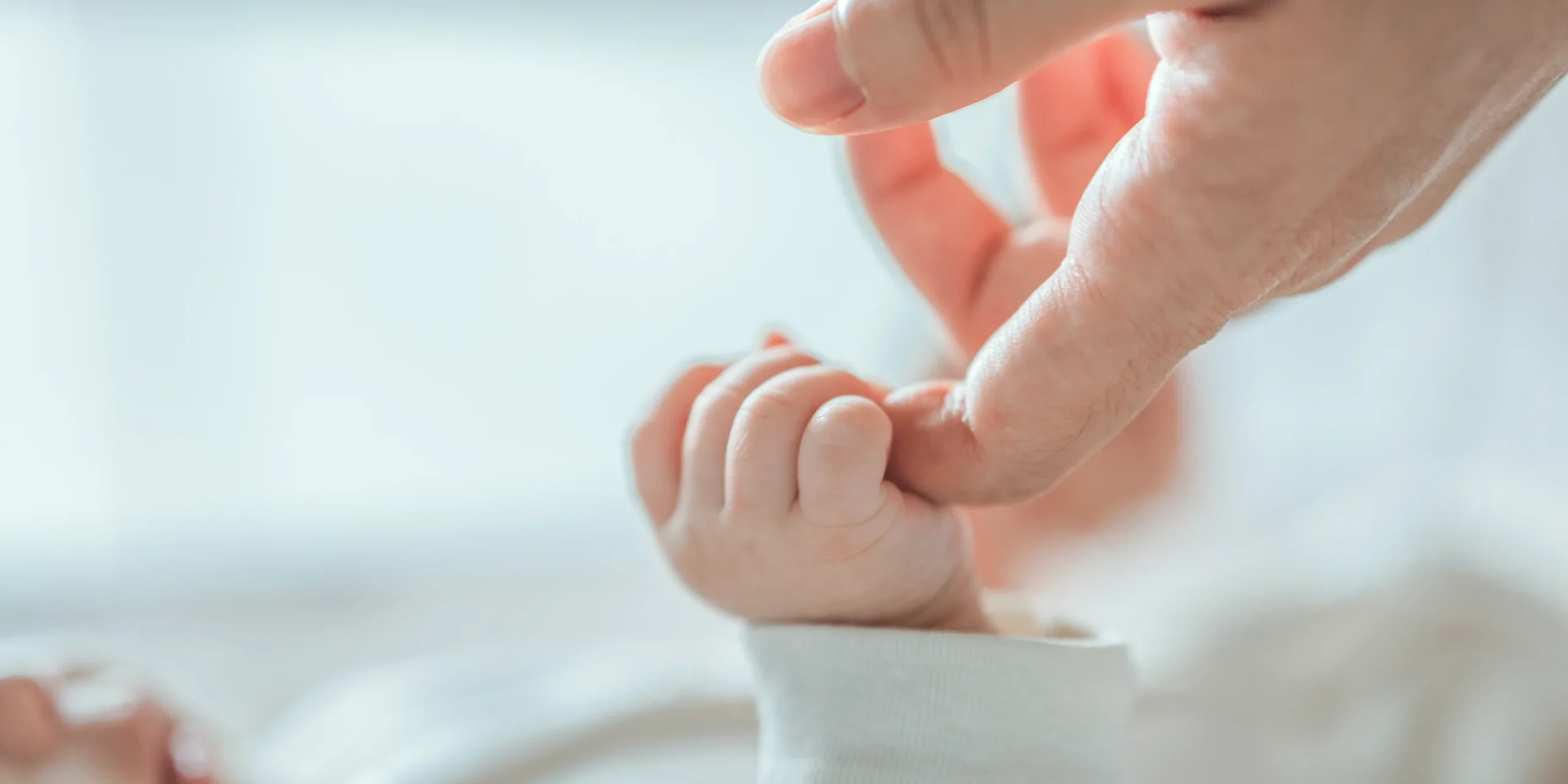 shutterstock_2493600455 Bebé sujetando el dedo índice de un adulto